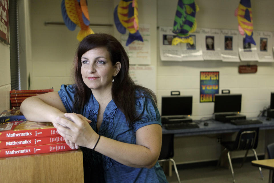 This Friday, March 16, 2012 photo shows Dawn Meehan, a teacher's assistant and writer, in her classroom at Gotha Middle School in Windermere, Fla. Meehan, 42, had a colonoscopy in February 2012, under deep sedation monitored by an anesthesia specialist; her insurance covered everything. Colonoscopies to screen for colon cancer usually aren't recommended until age 50 but Meehan had the exam because of symptoms for a common digestive disease. She was a low-risk patient and said if her colonoscopy doctor had offered it, she might have chosen light sedation. But even though the extra sedation is more costly, Meehan said patients who want it should get it, because otherwise some might "shy away from getting screened." (AP Photo/John Raoux)