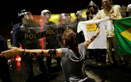 A demonstrator reacts near riot police officers during a protest against Brazil's President Michel Temer in front of the Planalto Palace in Brasilia, Brazil, May 18, 2017. REUTERS/Ueslei Marcelino