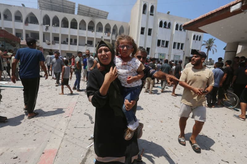 Palestinians flee a school where they sought refuge after it was hit by an Israeli attack in Deir el-Balah in the central Gaza Strip. Omar Ashtawy/APA Images via ZUMA Press Wire/dpa