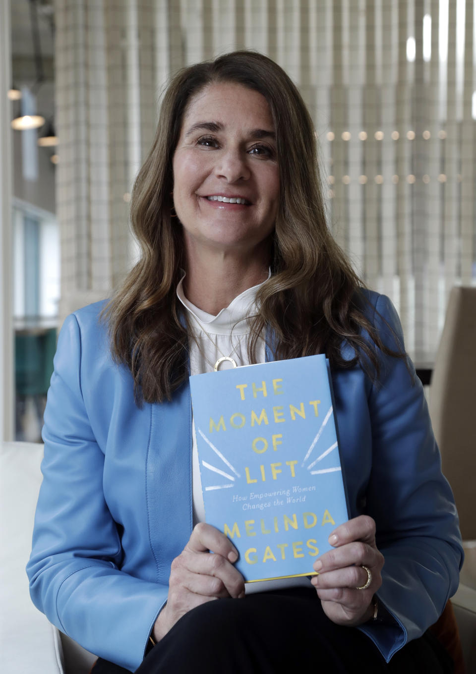 In this photo taken Thursday, April 18, 2019, Melinda Gates poses for a photo with her new book, "The Moment of Lift," in Kirkland, Wash. Her new book is a memoir from the former Microsoft tech business executive, outspoken feminist and public supporter of the MeToo movement. The Associated Press reviewed an advanced copy of the book ahead of its release Tuesday. (AP Photo/Elaine Thompson)