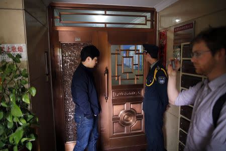 A journalist films as a security guard stands guard at the ground floor of the home of Zhang Xianling, whose son Wang Nan was killed by soldiers at the Tiananmen Square in 1989, in Beijing, in this April 24, 2014 file photo. REUTERS/Petar Kujundzic/Files