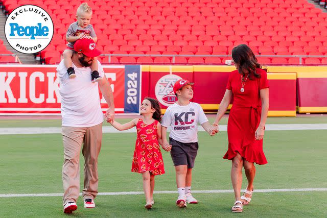 <p>Courtesy of Abby Lynne Photo</p> Porter Ellett and his wife Carlie walk on the field at Arrowhead Stadium with their three kids.