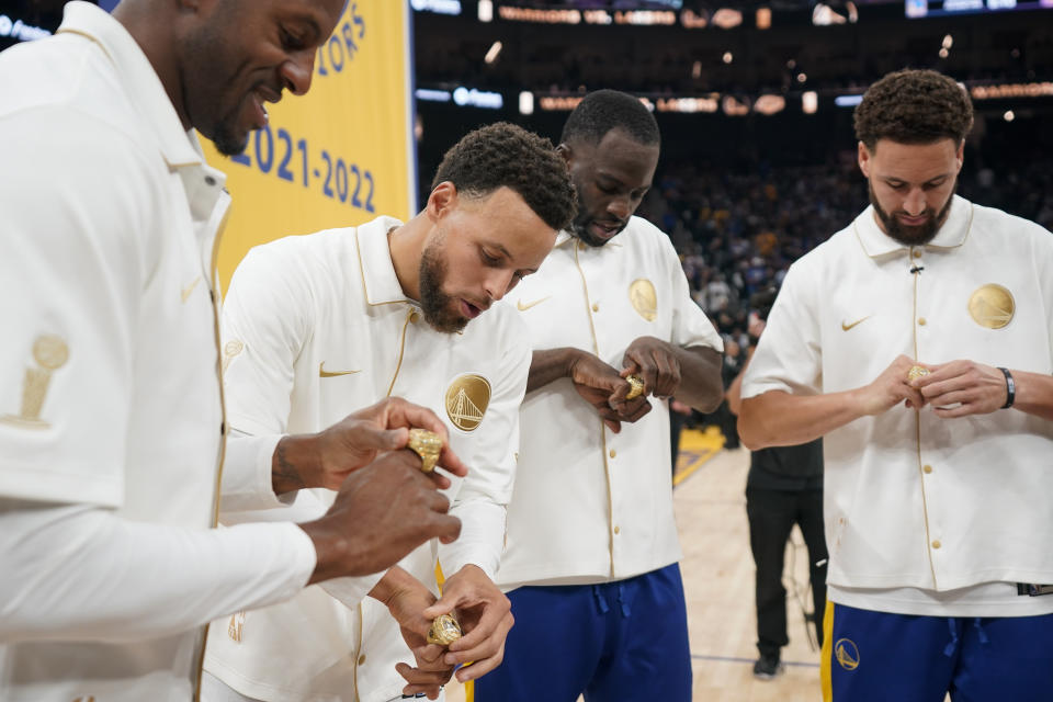 Golden State Warriors' Andre Iguodala, Stephen Curry, Draymond Green and Klay Thompson look at their 2021-2022 NBA championship rings before the team's basketball game against the Los Angeles Lakers in San Francisco, Tuesday, Oct. 18, 2022. (AP Photo/Godofredo A. Vásquez)