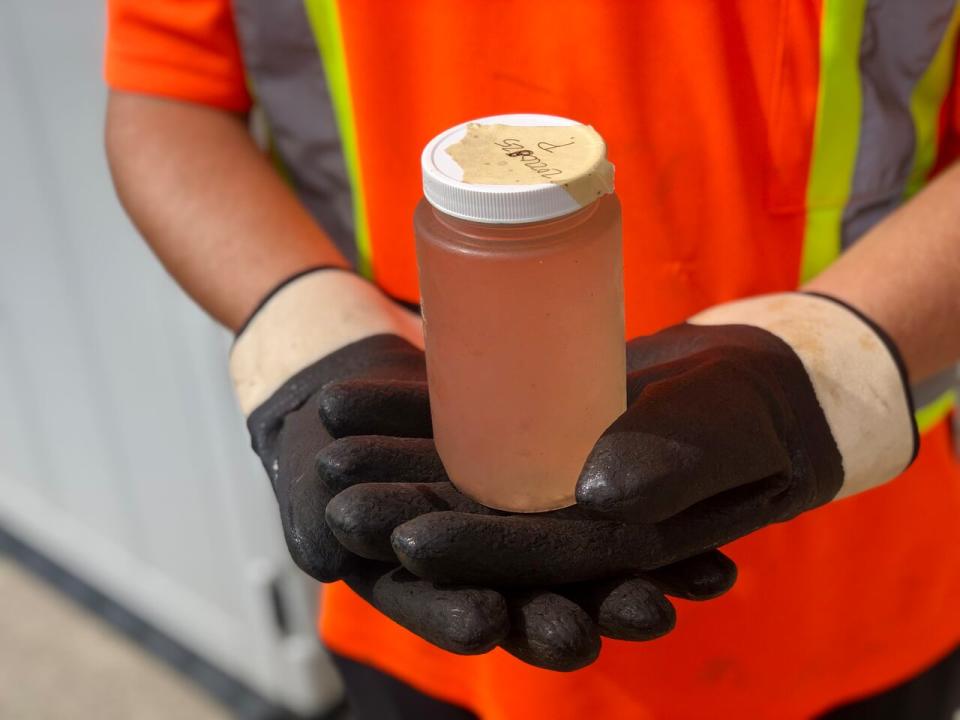 Andrew Nimetz, a shift operator at a London, Ont. wastewater treatment site, holds up a sample jar collected for researchers at nearby Western University.