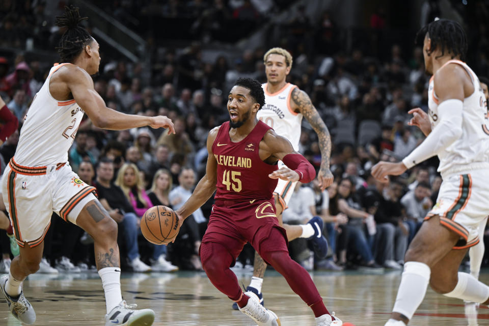Cleveland Cavaliers' Donovan Mitchell (45) drives against San Antonio Spurs' Devin Vassell, left, during the first half of an NBA basketball game, Saturday, Feb. 3, 2024, in San Antonio. (AP Photo/Darren Abate)