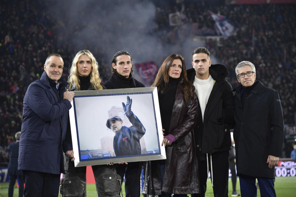 Family members hold a photo in remembrance of the one year anniversary of the death of Sinisa Mihajlovic, ahead of the Italian Serie A soccer match between Bologna and Roma, at Renato Dall'Ara Stadium, in Bologna, Italy, Sunday, Dec. 17, 2023. (Massimo Paolone /LaPresse via AP)