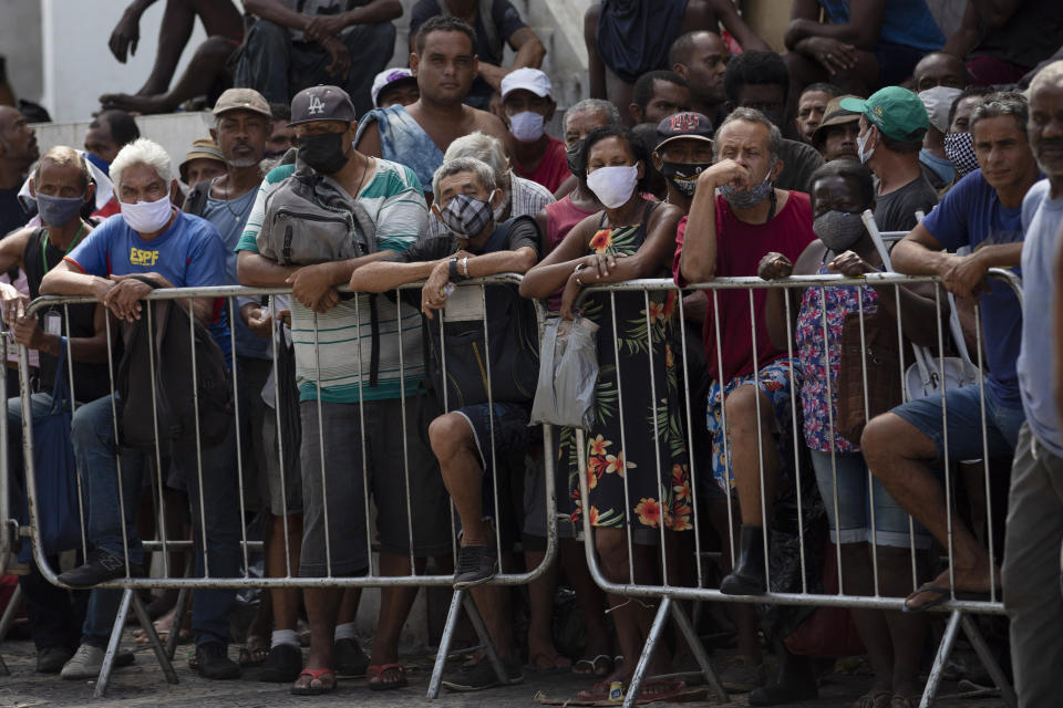 People wait in line for a meal donated by the Leao Xlll Foundation amid the COVID-19 pandemic in Rio de Janeiro, Brazil, Wednesday, April 7, 2021. (AP Photo/Silvia Izquierdo)