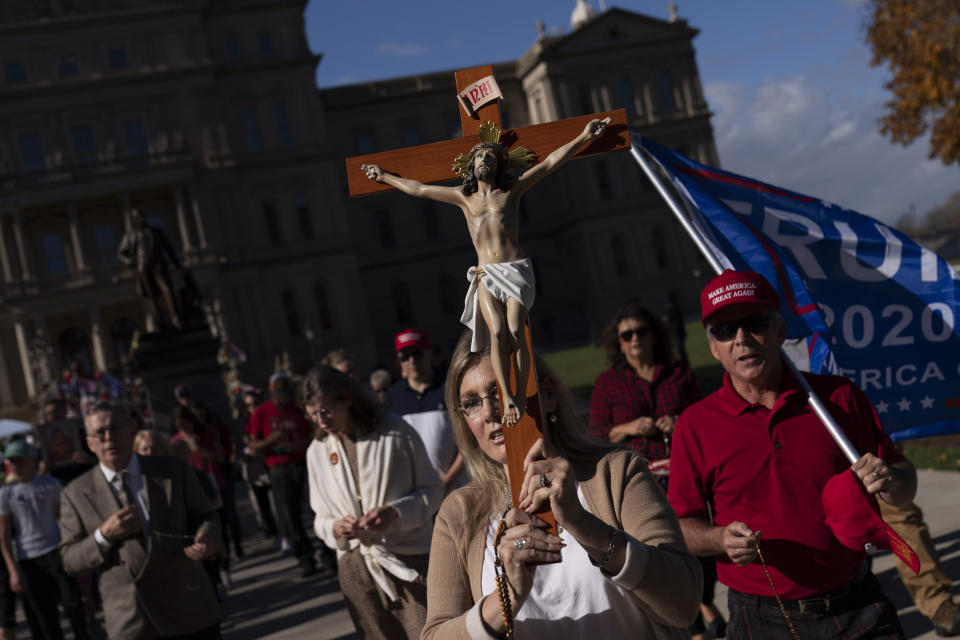 Worshippers pray during a protest with Trump supporters demonstrating against the presidential election results at the State Capitol in Lansing, Mich., Sunday, Nov. 8, 2020. (AP Photo/David Goldman)