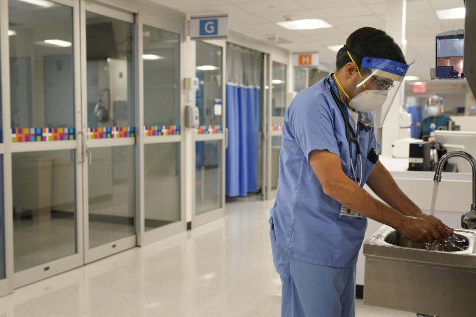 Medical personnel wash their hands while tending to patients in Bellevue Hospital in New York, Wednesday, Oct. 28, 2020. The rooms in this area have been outfitted to care for COVID-19 patients if there is a surge that overwhelms their usual critical care facilities. Hospitals in the city's public NYC Health and Hospitals' system have been upgrading their equipment, bracing for a potential resurgence of coronavirus patients, drawing on lessons learned in the spring when the outbreak brought the nation's largest city to its knees. (AP Photo/Seth Wenig)