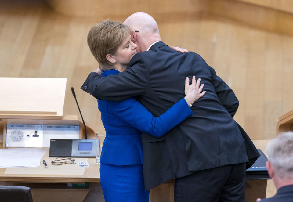 Outgoing Scottish First Minister Nicola Sturgeon and outgoing Deputy First Minister John Swinney hug before leaving the main chambe after her last First Minister's Questions (FMQs) in the main chamber of the Scottish Parliament in Edinburgh, Thursday March 23, 2023. (Jane Barlow/PA via AP)