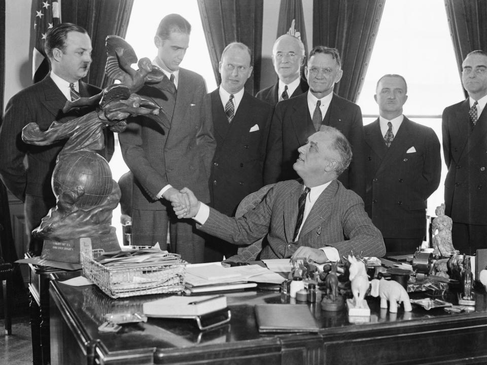 President Roosevelt holds the hand of Howard Hughes, motion picture producer and famous flyer, as the president hands him the Harmon International Trophy, in Washington, D.C., March 2.