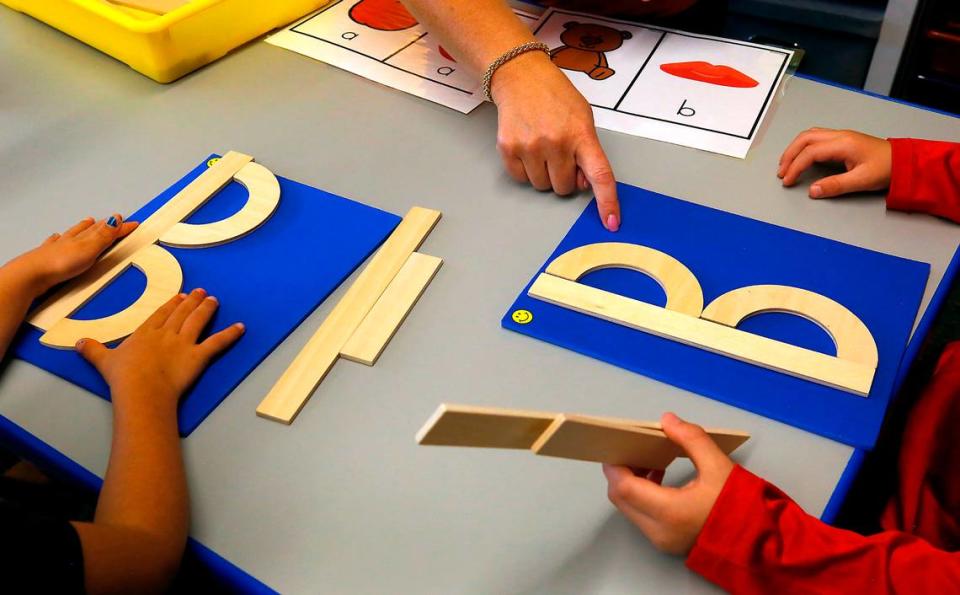 Kindergarten teacher Toni Cuello works with Desert Sky Elementary students to build letters of the alphabet using wooden shapes.