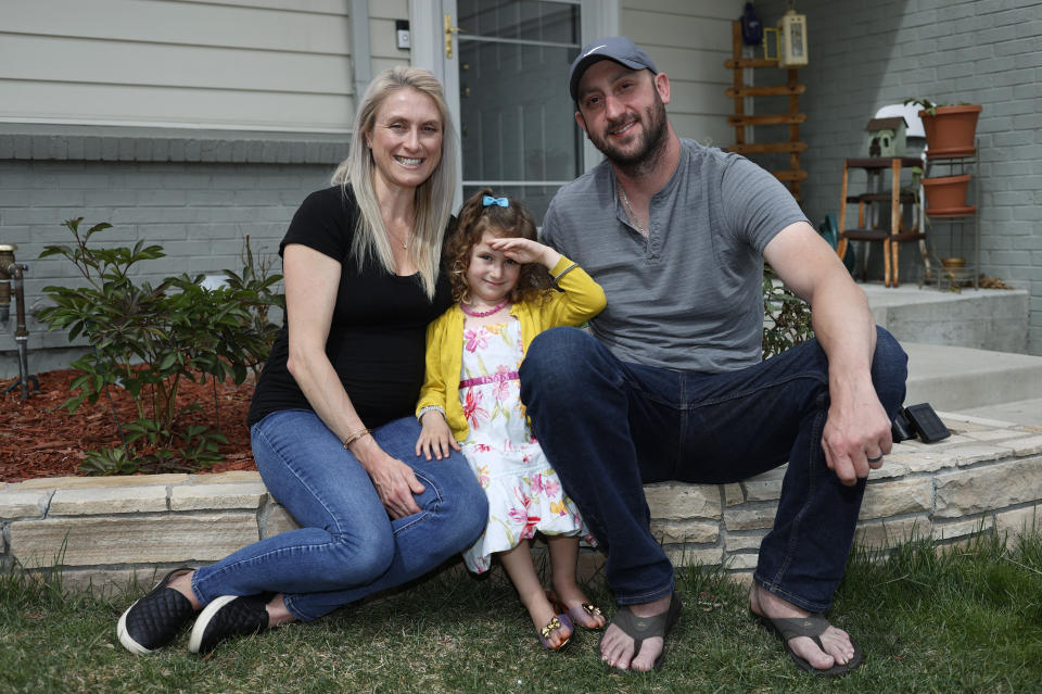 FILE - In this April 30, 2020, file photo, Eli Oderberg, right, sits with Katie Evers and their 4-year-old daughter, Everlee, outside their home in southeast Denver. Oderberg lost his job in a wave of layoffs in April, and he remains unemployed as he and his wife fear running out of money once their new baby arrives.  They are among millions of Americans struggling to pay bills as the coronavirus pandemic continues. (AP Photo/David Zalubowski, File)