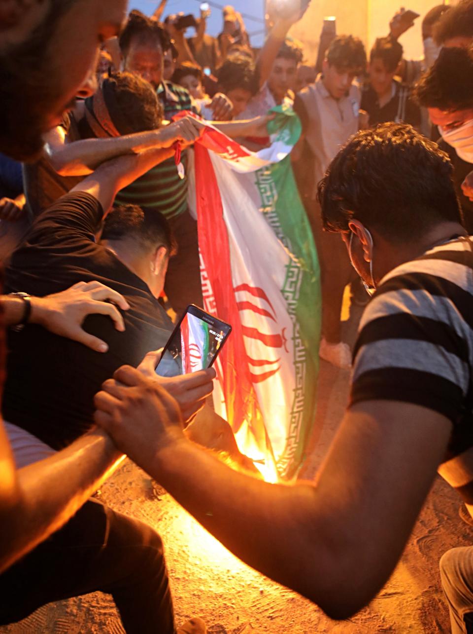 FILE - In this Friday, Sept. 7, 2018 file photo, protesters burn an Iranian flag after storming and burning the Iranian consulate building in Basra, Iraq. A falsely captioned version of this photo began circulating on social media as protests escalated in Iraq in early October 2019, incorrectly claiming that it shows protesters burning an Iranian flag in Baghdad as Iraqis held anti-government protests around the country. (AP Photo/Nabil al-Jurani, File)