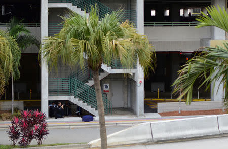 Law enforcement personnel take cover below a stairwell in a parking garage opposite a terminal after a shooter opened fire at a baggage carousel at Fort Lauderdale-Hollywood International Airport in Fort Lauderdale, Florida, U.S., January 6, 2017. REUTERS/Zachary Fagenson