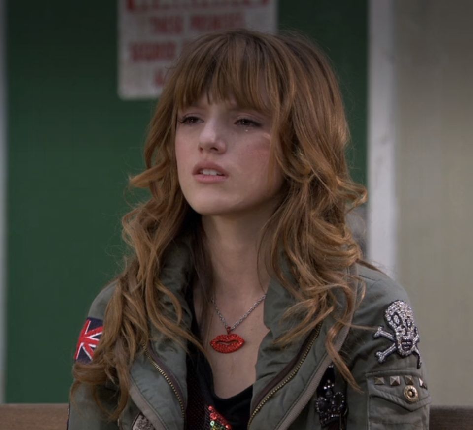 Bella as Cene with layered hair, wearing a detailed bomber jacket and a lips necklace in a scene from "Shake It Up"