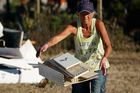 A woman tosses garbage on a pile following Hurricane Michael in Mexico Beach, Florida, U.S., October 13, 2018. REUTERS/Carlo Allegri