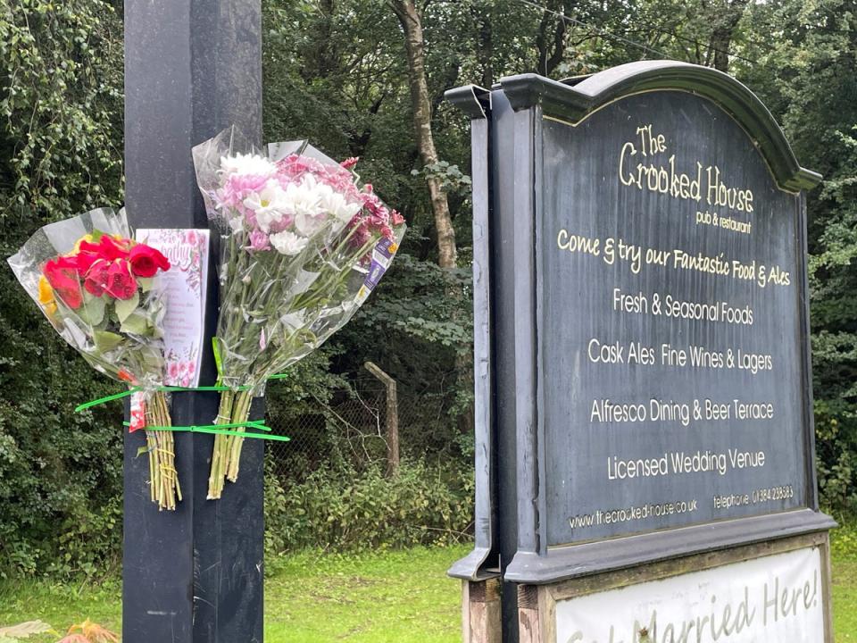 Flowers and a card left on the sign outside the remains of The Crooked House pub (Matthew Cooper/PA Wire)