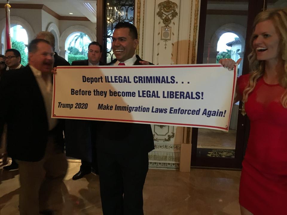 Guests hold up a sign about immigration at Mar-a-Lago during the Palm Beach Republican Party's Lincoln Day dinner on March 24, 2017.