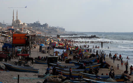 Palestinians swim to cool off in the Mediterranean Sea as others enjoy their time on a beach in the northern Gaza Strip July 13, 2018. REUTERS/Mohammed Salem