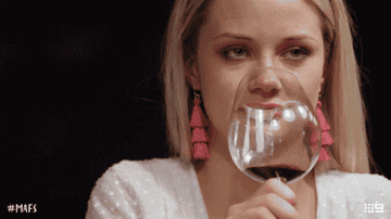 woman rolling her eyes while sipping a glass of wine