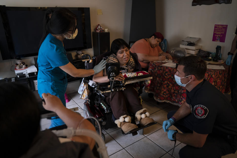 Pharmacist Stella Kim, left, and Torrance firefighter Trevor Borello, right, talk with Barbara Franco, who has muscular dystrophy, before administering the second dose of the Pfizer COVID-19 vaccine at her apartment, Wednesday, May 12, 2021, in Torrance, Calif. Teamed up with the Torrance Fire Department, Torrance Memorial Medical Center started inoculating people at home in March, identifying people through a city hotline, county health department, senior centers and doctor's offices, said Mei Tsai, the pharmacist who coordinates the program. (AP Photo/Jae C. Hong)