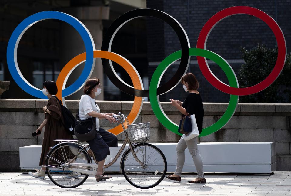 People walk by the Olympic rings installed by the Nippon Bashi bridge in Tokyo.