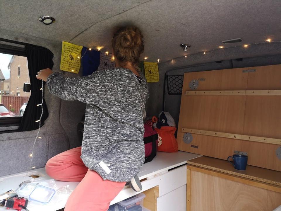 The writer sitting on a table hanging string lights up inside the van