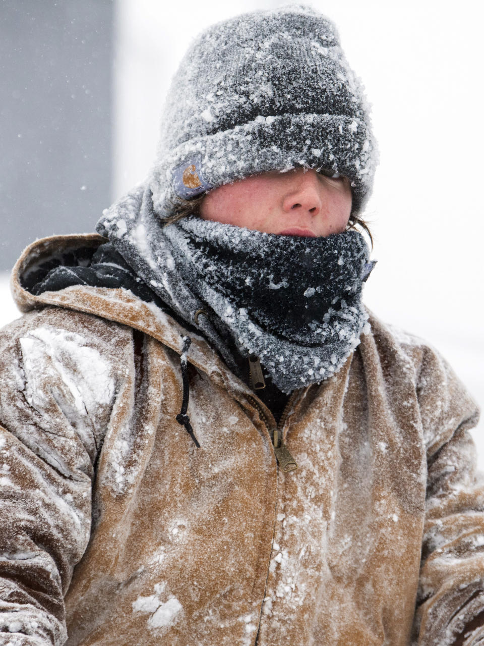 Barret Goff, covered in an icy drizzle, braves the heavy early morning snow to clear the Alan's Auto Sales lot with a snow blower on Thursday, Feb. 16, 2023, in Lincoln, Neb. (Kenneth Ferriera/Lincoln Journal Star via AP)