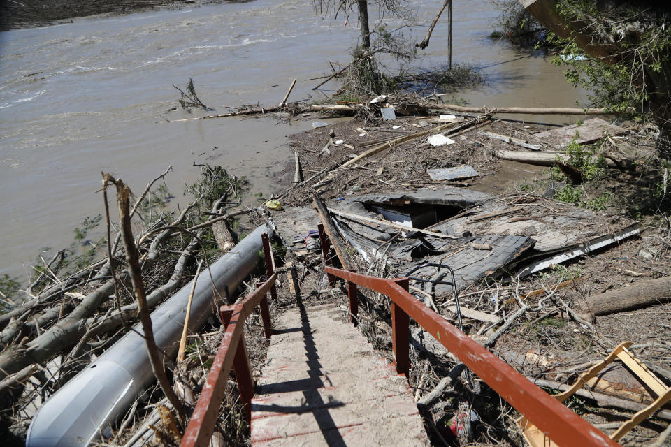 Debris litters the riverbank behind Dan Dionne's home, Wednesday, May 20, 2020, in Edenville, Mich. Some people living along two mid-Michigan lakes and parts of a river have been evacuated following several days of heavy rain that produced flooding and put pressure on dams in the area returned to the area to survey the damage. (AP Photo/Carlos Osorio)