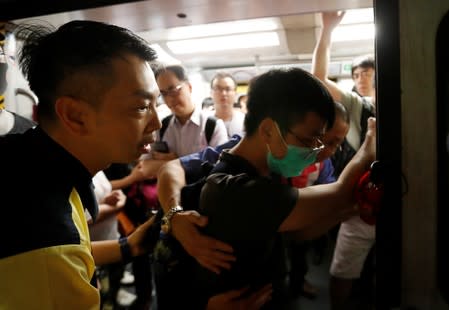 Mass Transit Railway (MTR) subway personnel try to prevent a protester from blocking the door of a train as protesters disrupt MTR services at Fortress Hill station in Hong Kong