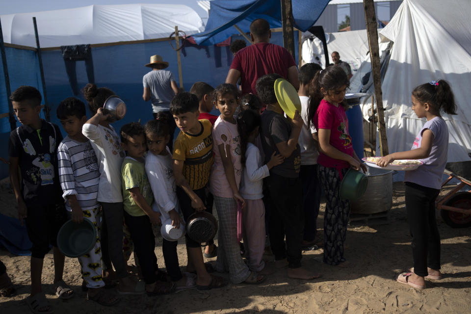 FILE - Palestinian children wait in line for a food distribution in a displaced tent camp, in Khan Younis, southern Gaza Strip, Wednesday, Oct. 25, 2023. With the Israel-Hamas war in its second month and more than 10,000 people killed in Gaza, trapped civilians are struggling to survive without electricity or running water. Each day has become a mind-numbing cycle of searching for bread and water and waiting in lines. A sense of desperation has strained Gaza's close-knit society. (AP Photo/Fatima Shbair, File)