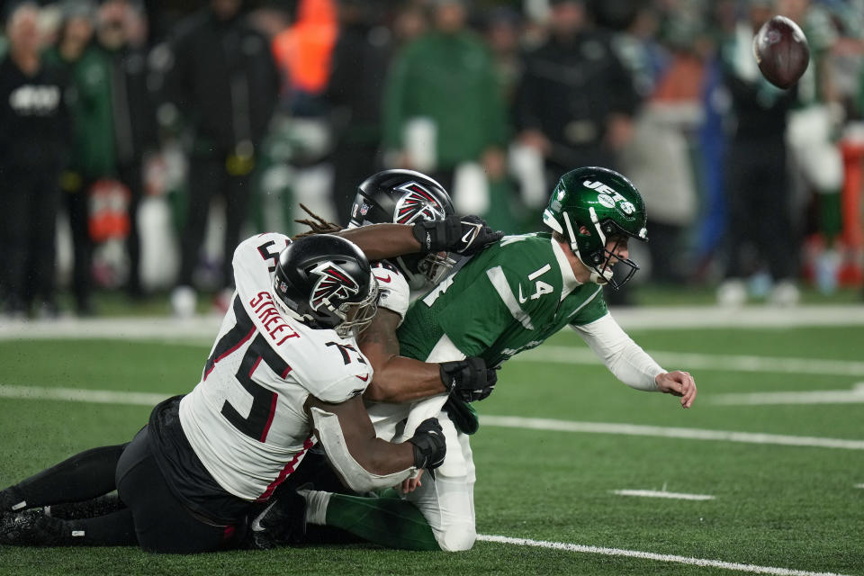 New York Jets quarterback Trevor Siemian (14) fumbles the ball as he is sacked by the Atlanta Falcons defensive tackle Kentavius Street (75) and linebacker Bud Dupree (48) during the fourth quarter of an NFL football game, Sunday, Dec. 3, 2023, in East Rutherford, N.J. (AP Photo/Seth Wenig)