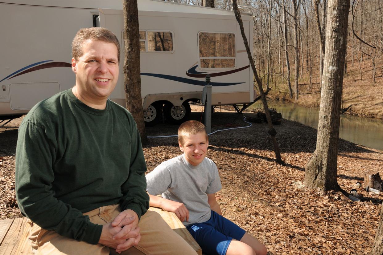 Middle age man and his son outside with RV