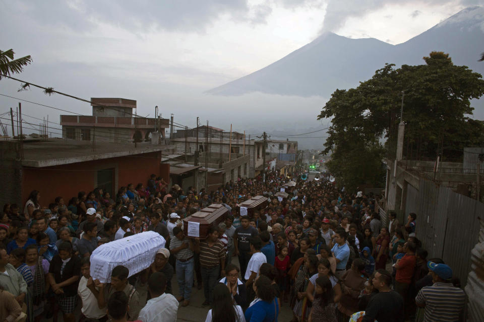 <p>People carry the coffins of seven people who died during the eruption of the Volcan de Fuego, which in Spanish means Volcano of Fire, in the background, to the cemetery in San Juan Alotenango, Guatemala, Monday, June 4, 2018. (Photo: Luis Soto/AP) </p>