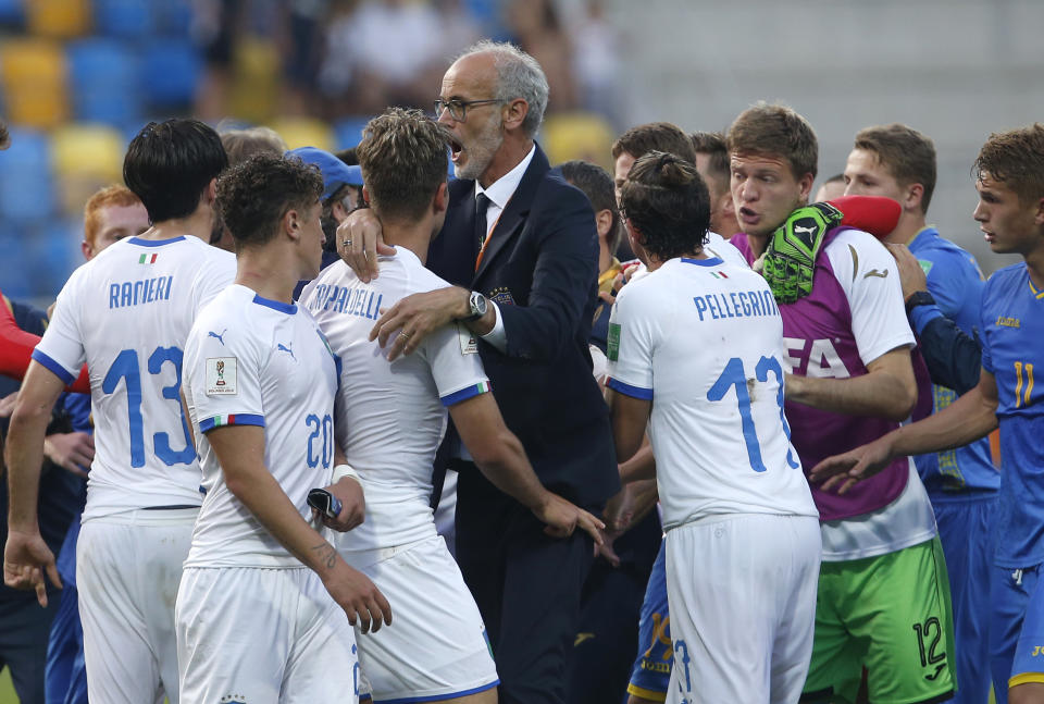 Italy coach Paolo Nicolato separates Italy and Ukraine players at the end of the semi final match between Ukraine and Italy at the U20 World Cup soccer in Gdynia, Poland, Tuesday, June 11, 2019. (AP Photo/Darko Vojinovic)