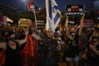 Protesters hold signs during a demonstration against Israel's government in Rabin square in Tel Aviv, Israel, Saturday, July 11, 2020. Thousands of Israelis gathered Saturday to protest the new government's failure to address economic woes brought by the coronavirus, directing their anger at Prime Minister Benjamin Netanyahu who is seeing his support plummeting. The signs say"war, pour the money. (AP Photo/Ariel Schalit)