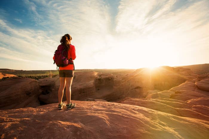 A woman hiking, looking out at the landscape