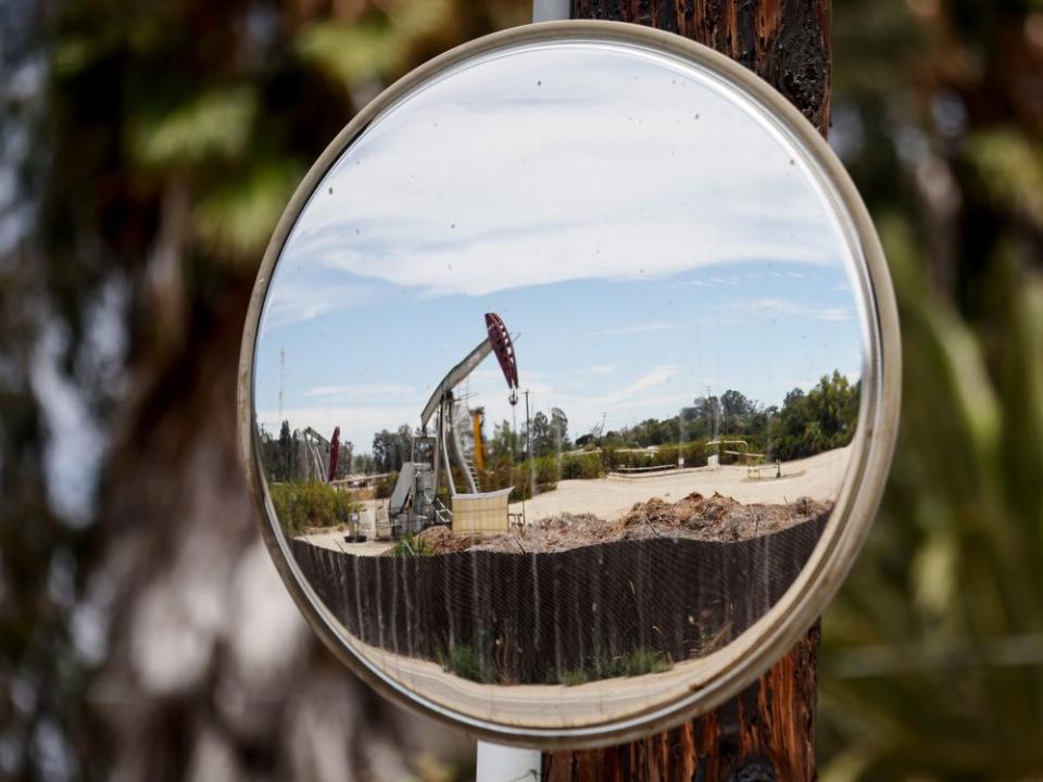  An oil pumpjack is reflected in a mirror as it operates on Aug. 5, 2022, near Ventura, Calif.