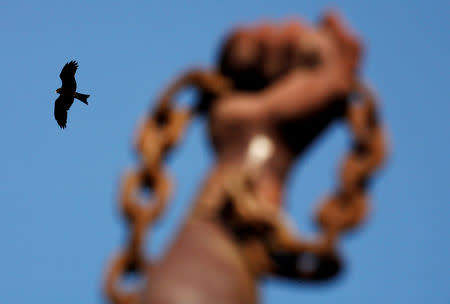 FILE PHOTO: A bird flies past a statue commemorating the liberation of slaves on Goree Island near Senegal's capital Dakar, March 16, 2007. REUTERS/Finbarr O'Reilly