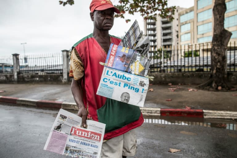 A newspaper vendor looks for customers in Libreville on August 29, 2016 while displaying local papers reporting on the outcome of Gabons's presidential elections