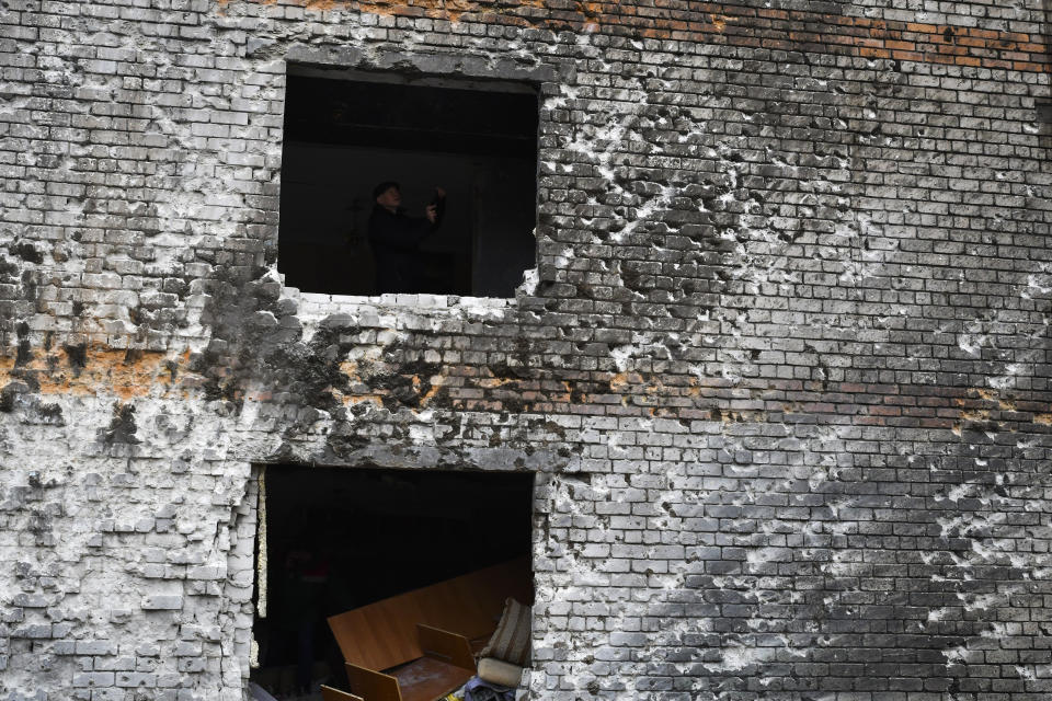 A local resident is seen in a window hole of an apartment building damaged in the night following a Russian rocket attack in Zaporizhzhya, Ukraine, Monday, Jan. 16, 2023. (AP Photo/Andriy Andriyenko)