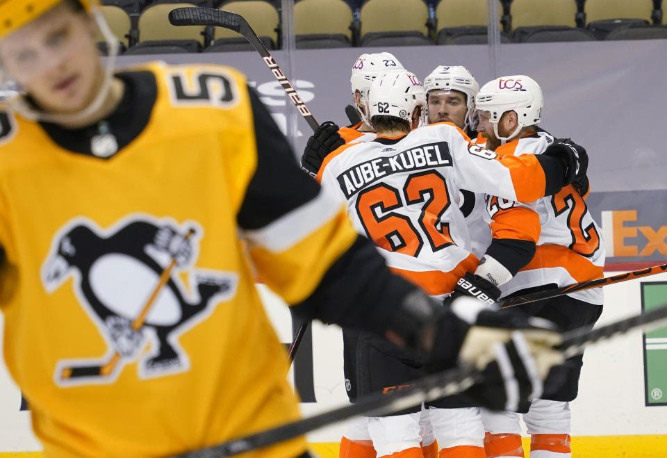 Pittsburgh Penguins' Jake Guentzel, left, skates away as Philadelphia Flyers' Claude Giroux, right, celebrates with teammates after scoring during the second period of an NHL hockey game Thursday, March 4, 2021, in Pittsburgh. (AP Photo/Keith Srakocic)