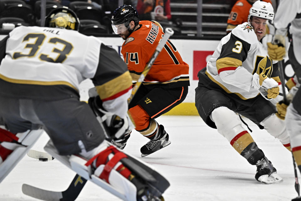 Anaheim Ducks center Adam Henrique, center, prepares to shoot against Vegas Golden Knights goaltender Adin Hill, left, and defenseman Brayden McNabb, right, scoring a goal during the first period of an NHL hockey game in Anaheim, Calif., Wednesday, Dec. 28, 2022. (AP Photo/Alex Gallardo)