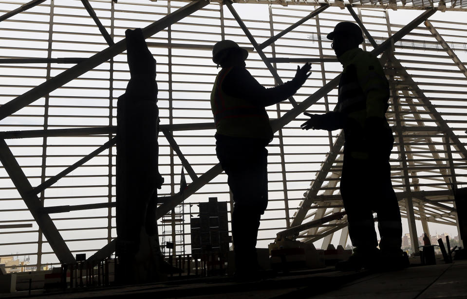 In this Sunday, Dec. 16, 2018 photo, construction workers talk in front of a statue of Ramses II, a 3000-year-old Pharaoh of Egypt, at the Grand Egyptian Museum under construction in Giza, Egypt, Sunday, Dec. 16, 2018. Thousands of Egyptians are laboring in the shadow of the pyramids to erect a monument worthy of the pharaohs. The Grand Egyptian Museum has been under construction for well over a decade and is intended to show off Egypt’s ancient treasures while attracting tourists to help fund its future development. (AP Photo/Amr Nabil)