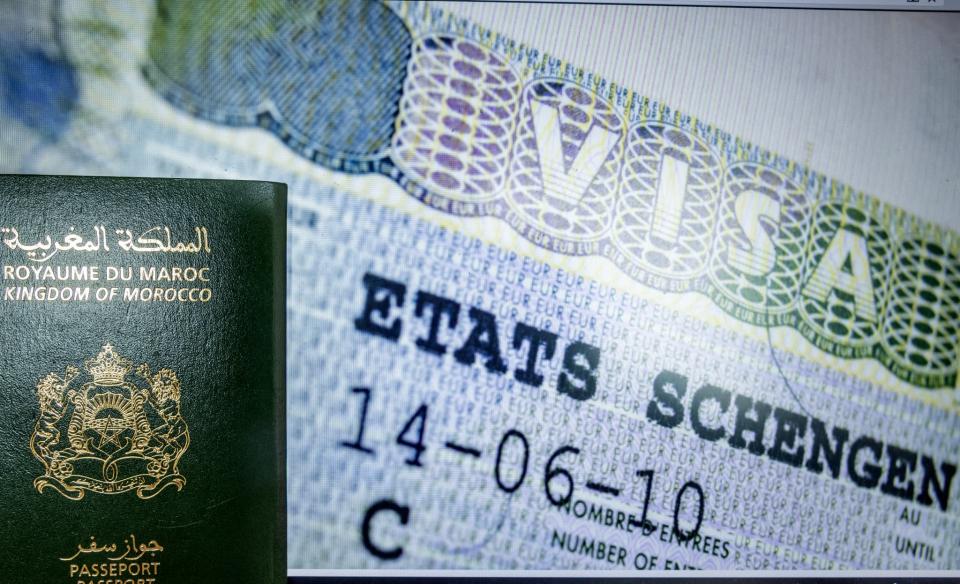 Une photo prise le 28 septembre 2021 dans la capitale marocaine Rabat montre un passeport marocain adossé à un visa Schengen. Paris va fortement réduire le nombre de visas accordés aux personnes originaires d'Algérie, du Maroc et de Tunisie. - FADEL SENNA / AFP