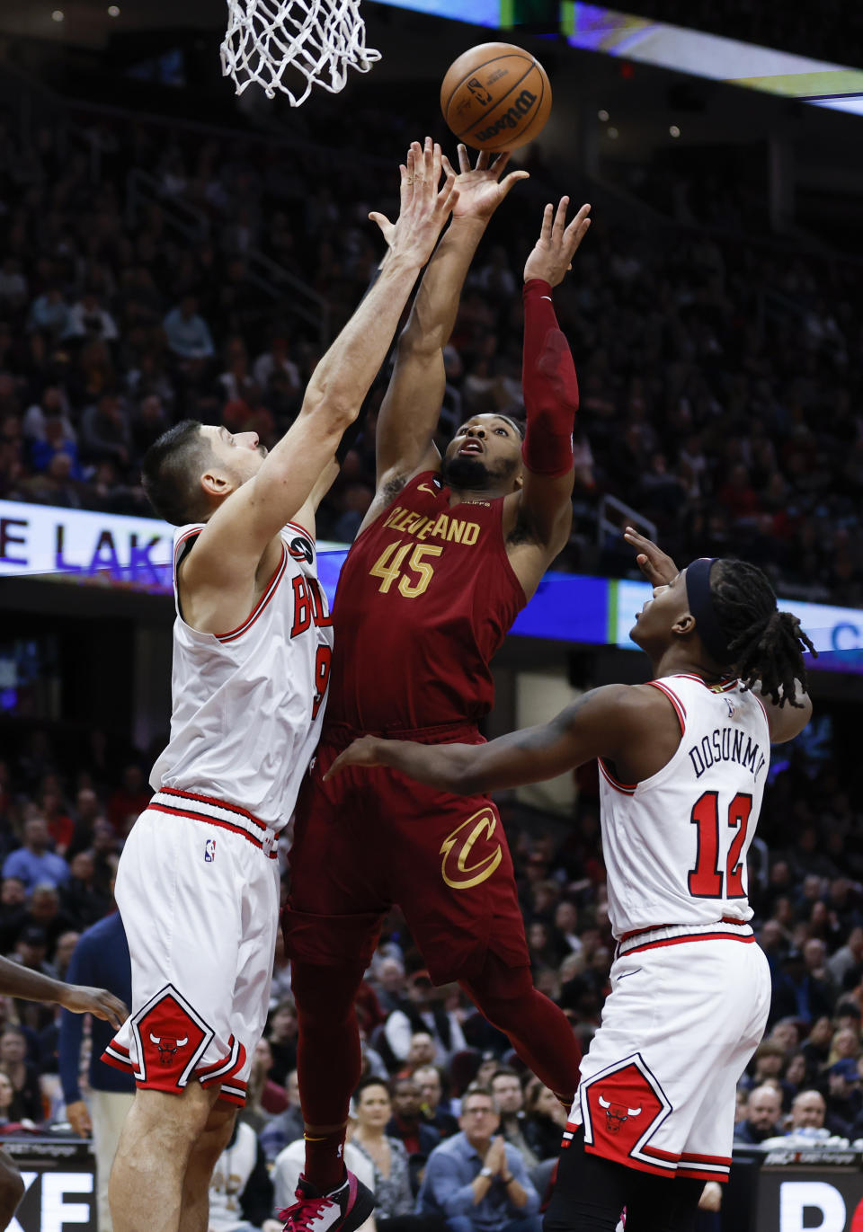 Cleveland Cavaliers guard Donovan Mitchell (45) shoots against Chicago Bulls center Nikola Vucevic (9) and guard Ayo Dosunmu (12) during the second half of an NBA basketball game, Monday, Jan. 2, 2023, in Cleveland. (AP Photo/Ron Schwane)