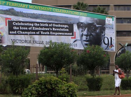 A Zimbabwean woman walks past a billboard with a birthday message for President Robert Mugabe inside the ZANU PF Hadquarters in Harare, February 25, 2015. REUTERS/Philimon Bulawayo