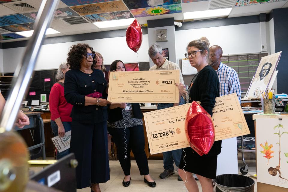 Topeka High art teacher Amy Cline right, reacts to receiving two grants Tuesday morning from Topeka Public Schools Foundation executive director Pamela Johnson-Betts, left. The bigger grant, for nearly $5,000, will be used for traveling printmaking labs for the district.
