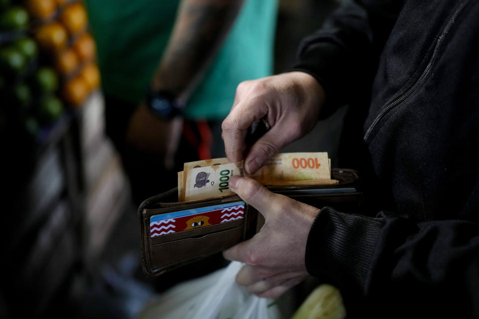 FILE - A shopper reaches for a 1,000 pesos banknote, in Buenos Aires, Argentina, Sept. 1, 2023. Artists of the Argentine Money Art movement paint the depreciated local currency and then share their work on social media. The artwork then fetches prices ranging from 40,000 to 70,000 pesos domestically and as much as $300 abroad. (AP Photo/Natacha Pisarenko, File)